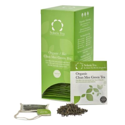 Badger and Dodo Coffee Roasters: The box of Solaris Organic Chun Mee Green Tea, open to reveal individual packets, sits elegantly with one packet in front, surrounded by loose leaves and a tea bag. The green box is labeled in white text.
