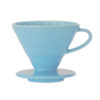 Badger and Dodo Coffee Roasters: The Hario V60 Colours Ceramic Dripper, with its blue color, features a conical design and handle for easy brewing. It fits securely on any cup or carafe, and its interior ridges ensure optimal extraction.