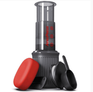 Badger & Dodo. Aeropress Go Travel Kit with red travel case, scoop, and stirrer, all accessories neatly arranged on a white background.