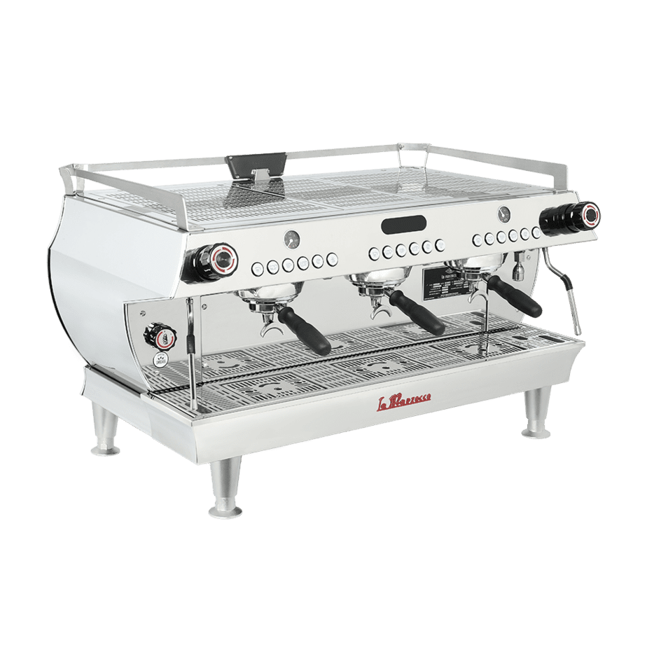 Badger and Dodo Coffee Roasters: The La Marzocco GB5 is a stainless steel commercial espresso machine boasting three group heads and portafilters. Its sleek, modern design features knobs and dials on the front panel, while sturdy legs provide elevation and stability.