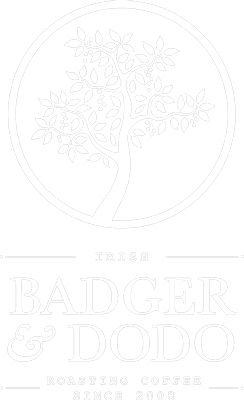 Badger and Dodo Coffee Roasters: The logo of Badger & Dodo features a stylized white tree in a circle on a gray background, embodying elegance. Below, the text reads: Irish Badger & Dodo Roasting Coffee Since 2008. The design subtly incorporates a badger footer to complete its unique charm.