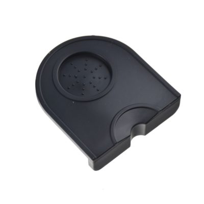 Badger and Dodo Coffee Roasters: The Dropped Edge Tamping Mat is a black plastic, semicircular drip tray with a textured surface, featuring raised dots for grip and a dropped edge for secure positioning.