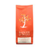 Badger and Dodo Coffee Roasters: The bright orange Badger & Dodo Hot Chocolate by Ó Conaill Chocolate bag features a stylized tree with red and yellow leaves. The logo and description appear in elegant white text, promising a delightful cocoa experience.