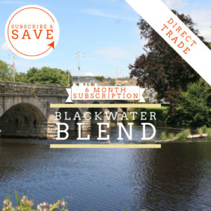 Badger and Dodo Coffee Roasters: A serene riverside scene reveals an ancient stone bridge over a peaceful river, flanked by trees and buildings. Text invites you to explore the Pay Once 6 Month Coffee Subscription Blackwater Blend with options like Subscribe & Save and highlighting its Direct Trade benefits.