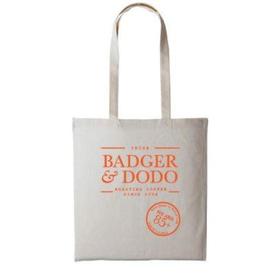 Badger and Dodo Coffee Roasters: The Badger and Dodo Tote Bag (Orange) is a beige canvas bag featuring Badger & Dodo Roasting Coffee Since 2008 next to a vibrant orange circle stating We are 85+.