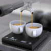 Badger & Dodo. Two cups of espresso are being brewed on the Timemore Black Mirror Plus 2 scale beneath a coffee machine portafilter.