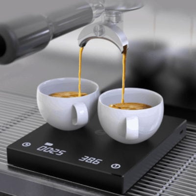 Badger & Dodo. Two cups of espresso are being brewed on the Timemore Black Mirror Plus 2 scale beneath a coffee machine portafilter.