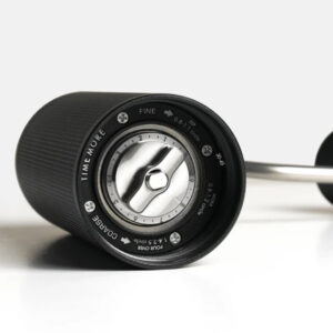 Badger & Dodo. A close-up of the Timemore Grinder Chestnut espresso in black, lying on its side and showcasing its grind size adjustment dial.