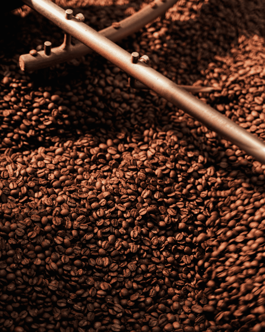 Badger & Dodo. Roasted coffee beans being stirred with a metal rod in a coffee roasting machine, ready for our wholesale partner to enjoy premium quality and flavor.