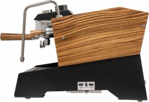 A modern, high-end espresso machine with a black metal body, chrome brew group, and wooden side panels and handles. It features a portafilter, a steam wand, and a minimalist front panel with the Nurri logo.